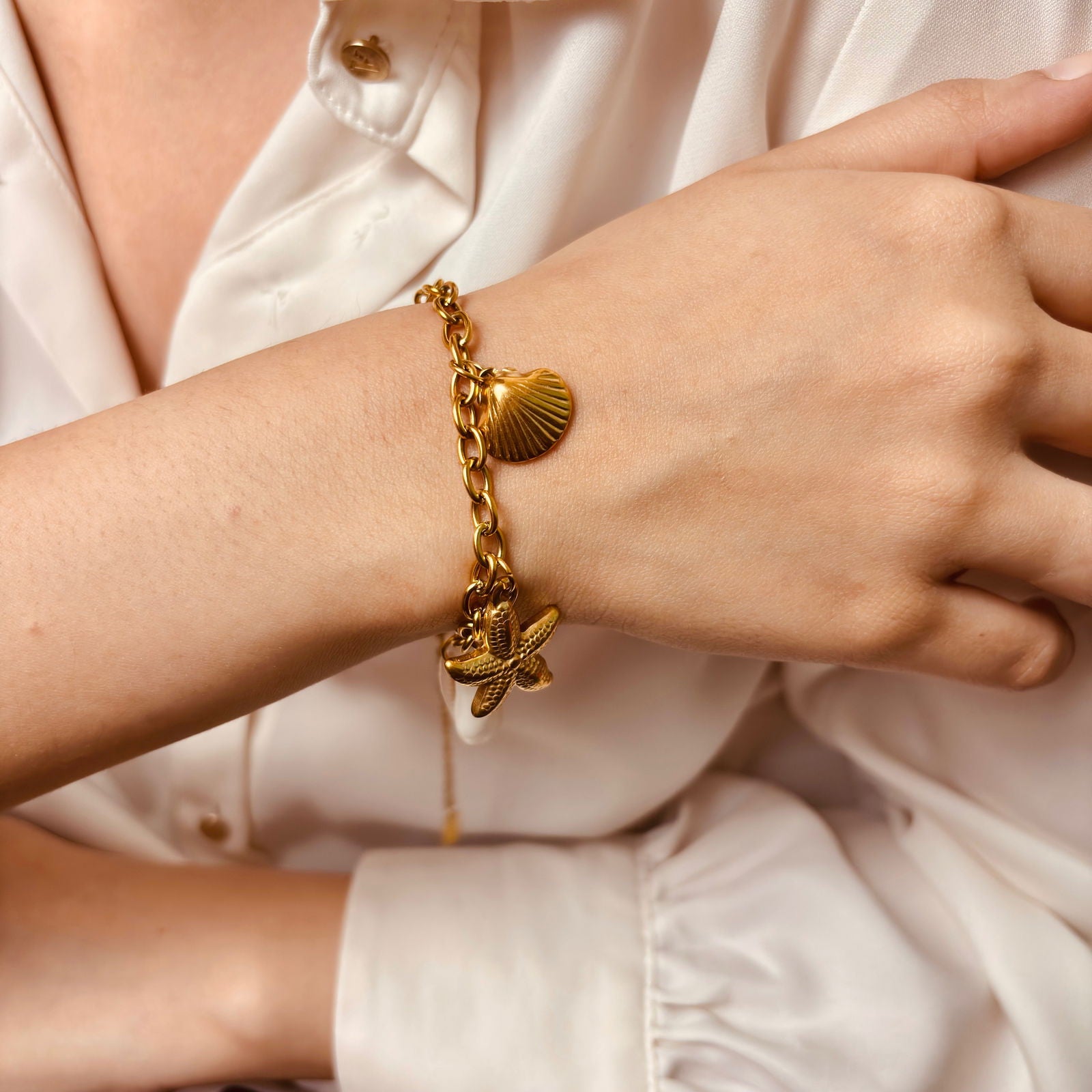Model's hand showing side profile of shell and starfish beach charm bracelet - dainty chic minimalist elegant gold plated bracelet - hypoallergenic anti‑tarnish waterproof nickel‑free lead‑free gold plated bracelet