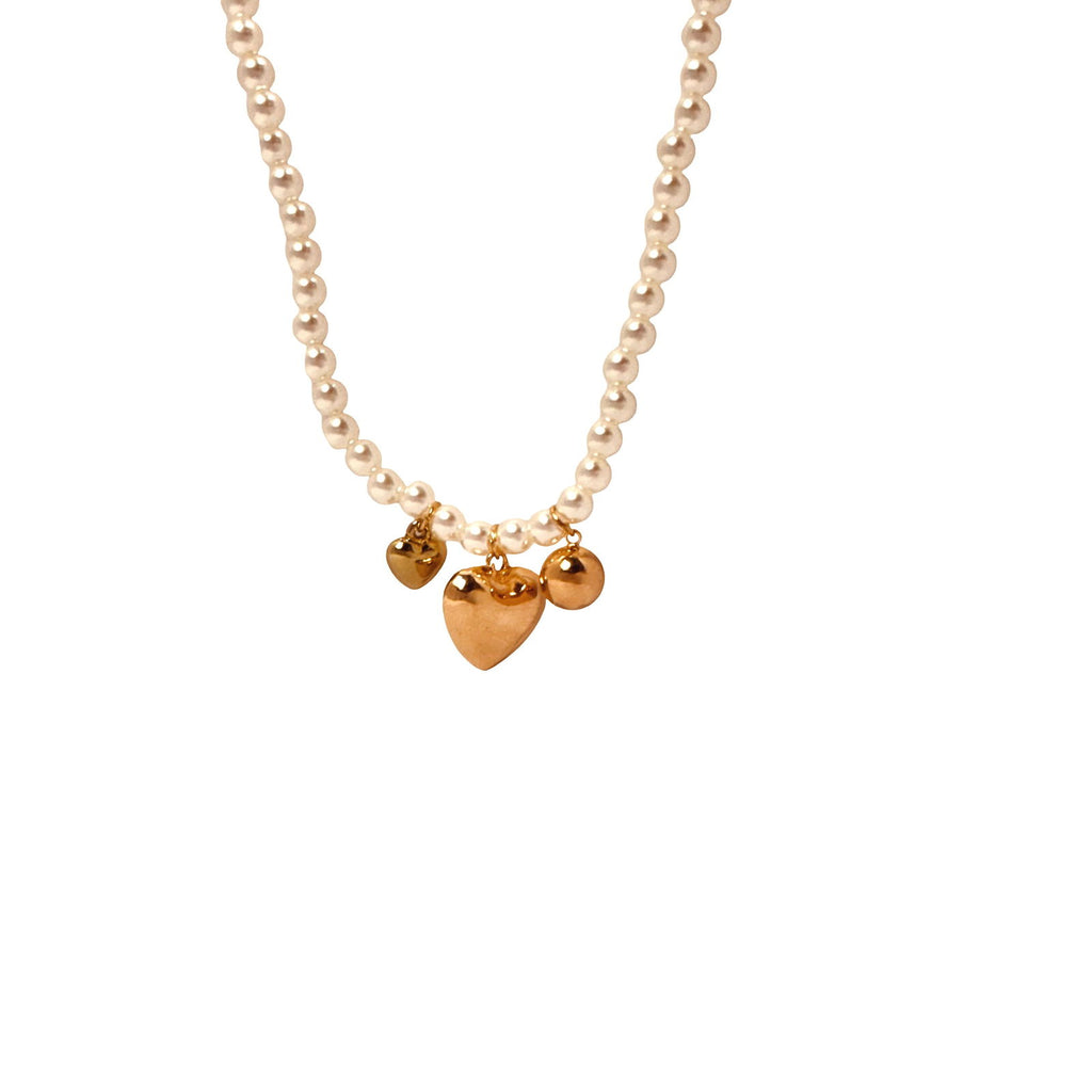 Flat-lay of pearl and heart charm necklace – soft romantic tones