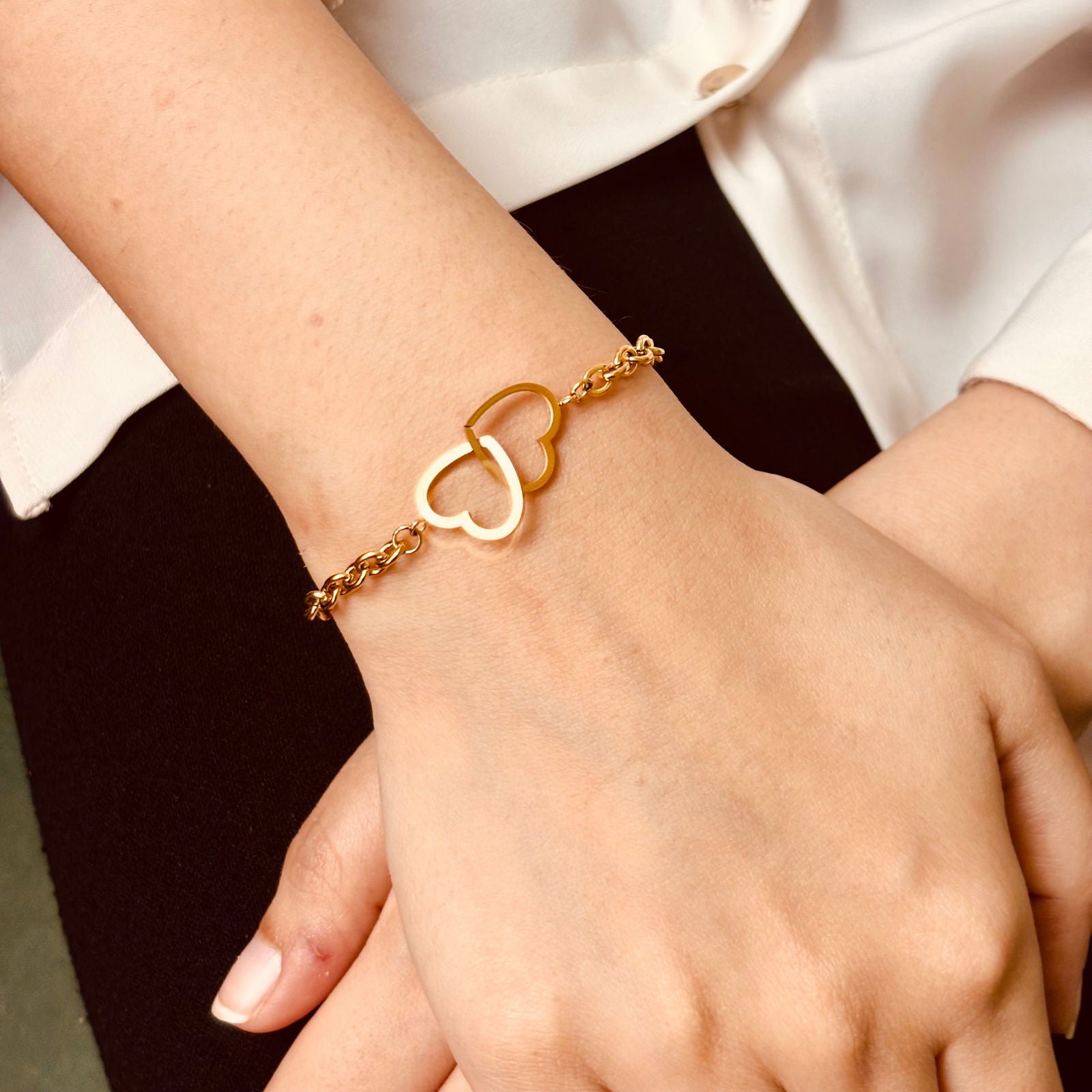Model's hand top shot of linked heart bracelet showing shine and elegance