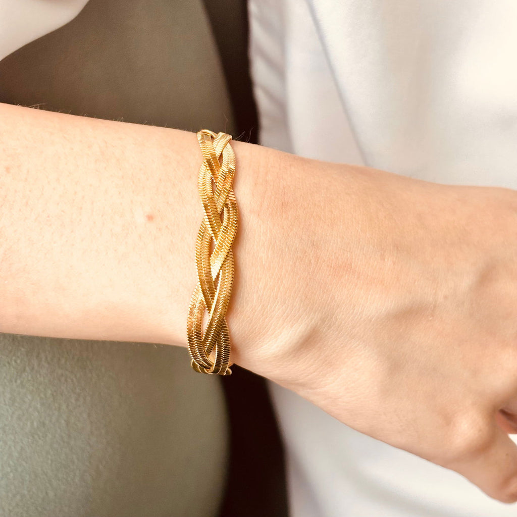 Model's hand close-up of braided gold bracelet highlighting snake chain weave and thickness