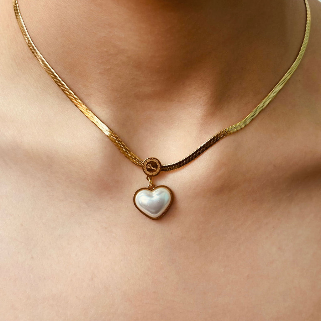 Front shot of pendant on model's neck as background showing lustrous pearl surface and chain gold plating