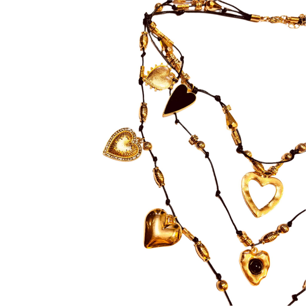 Side profile shot of two-tone heart necklace showing black cord and black and golden two-tone hearts details - boho style