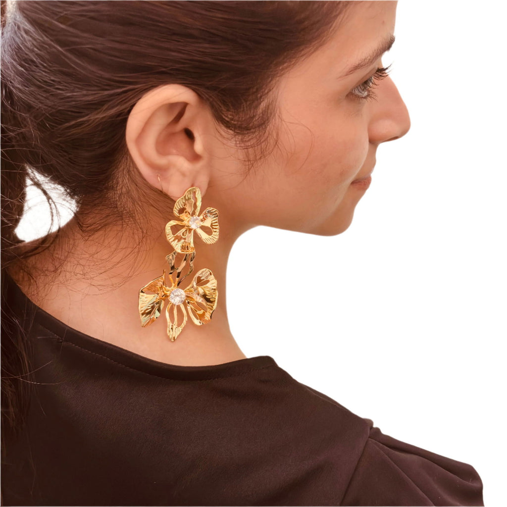 Model's angled image of large flower studs with reflective gold finish - Statement elegant gold plated earrings - hypoallergenic anti‑tarnish waterproof nickel‑free lead‑free gold plated earrings - scratch‑resistant fade‑resistant water‑resistant gold plated earrings