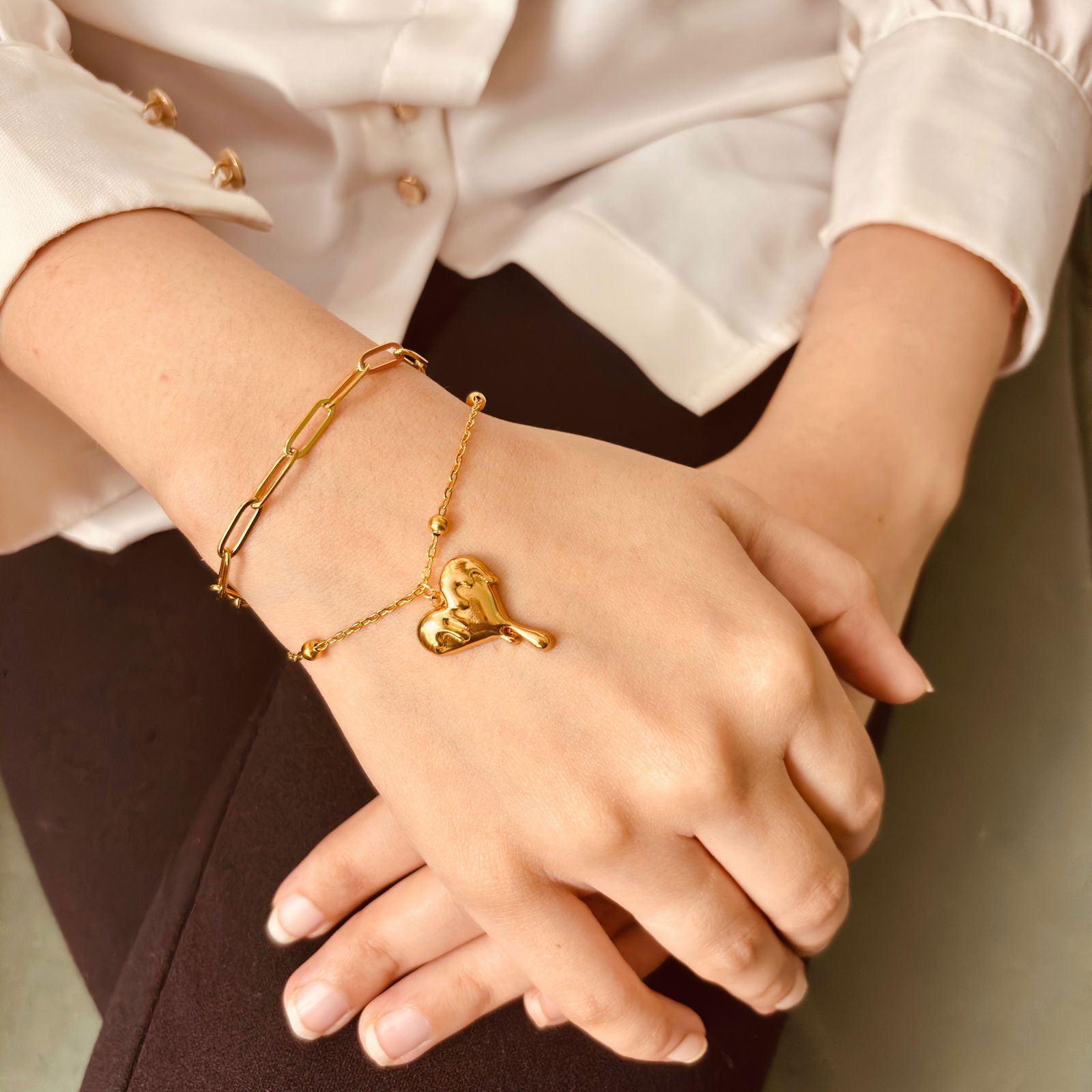 Model's hand shot showing flowing chain structure and heart detail - dainty 18K gold plated stainless steel heart bracelet - hypoallergenic 18K gold plated stainless steel sleek bracelet anti-tarnish - Rakhi gifts for sister under 2000 - jewelry Raksha Bandhan gifts - gold bracelet under 2000