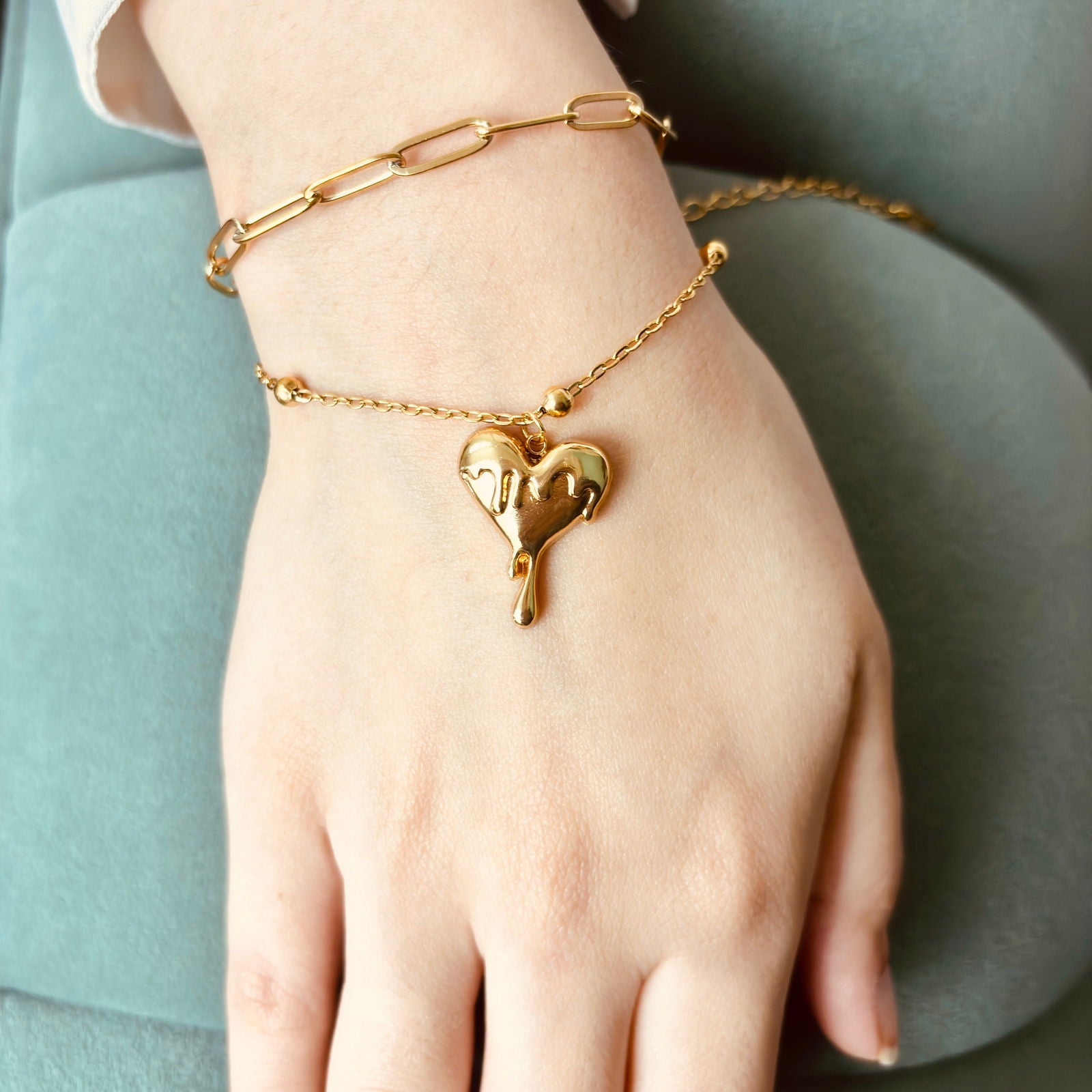 Close-up of melting heart charm and layered bracelet chains - hypoallergenic anti‑tarnish waterproof nickel‑free lead‑free gold plated bracelet - dainty chic minimalist elegant gold plated bracelet