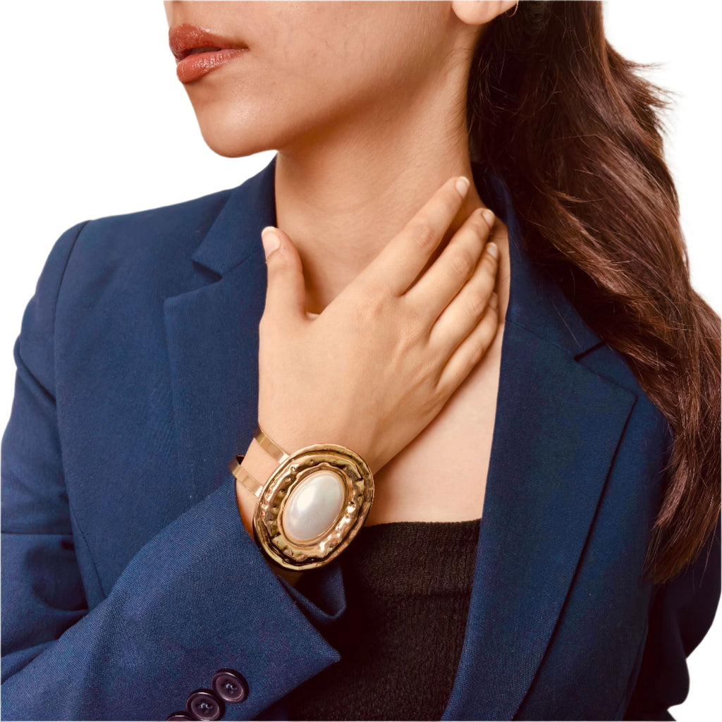 Front shot of model with angled bracelet view showcasing 18K gold plated large pearl hammered stainless steel bracelet with open bangle style - 18K gold plated anti-tarnish waterproof hypoallergenic oversized pearl hammered cuff bracelet