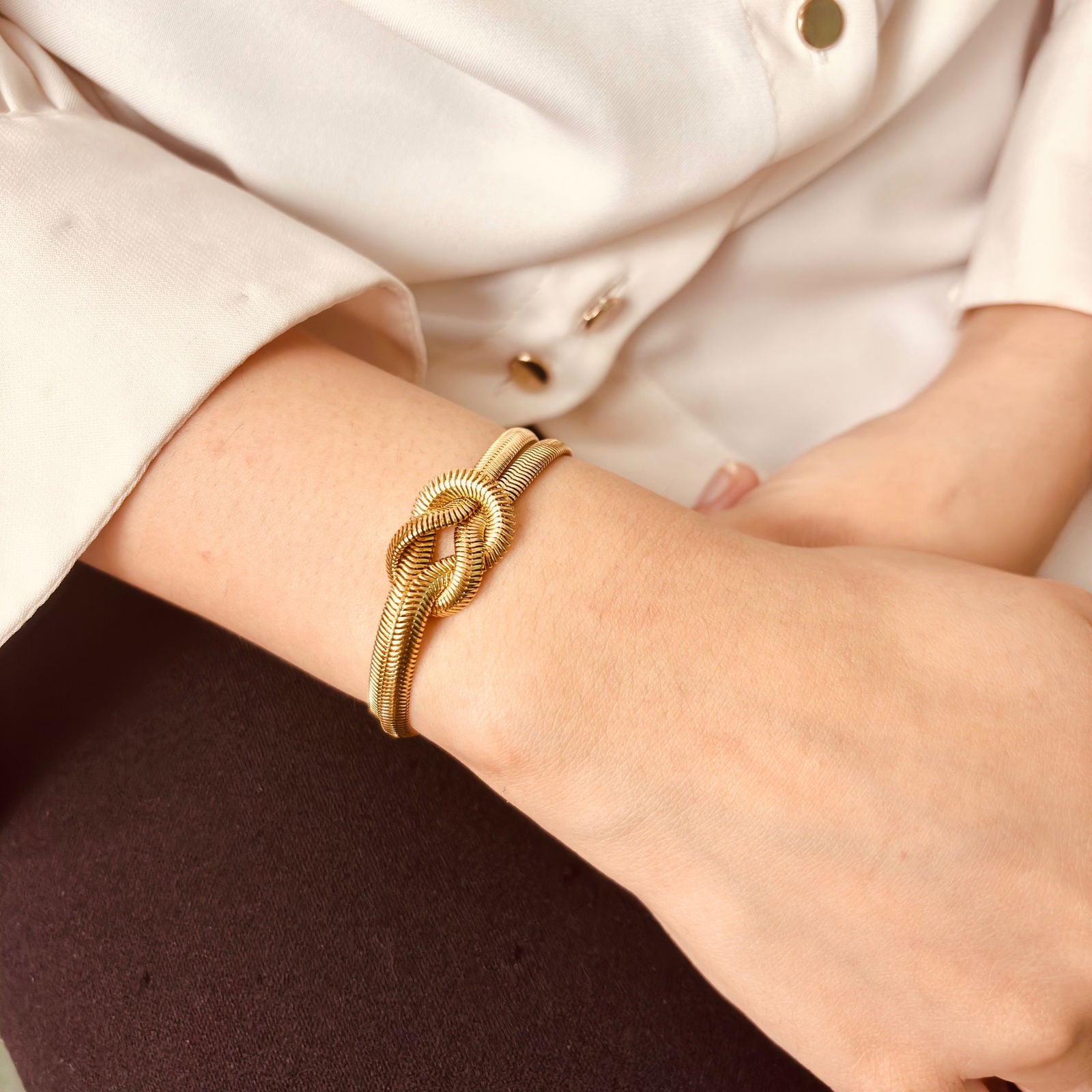 Model's hand flat display of hypoallergenic 18K gold plated snake chain knot stainless steel bracelet anniversary gift for her ideas under 2000 – minimalist gold bangle under 2000 - elegant anti-tarnish 18K gold plated stainless steel snake chain bracelet birthday gift for her under 2000 - waterproof chic gold plated snake chain dainty bracelet festive gift under 2000 - Rakhi gifts for sister under 2000 - jewelry Raksha Bandhan gifts - gold bracelet under 2000