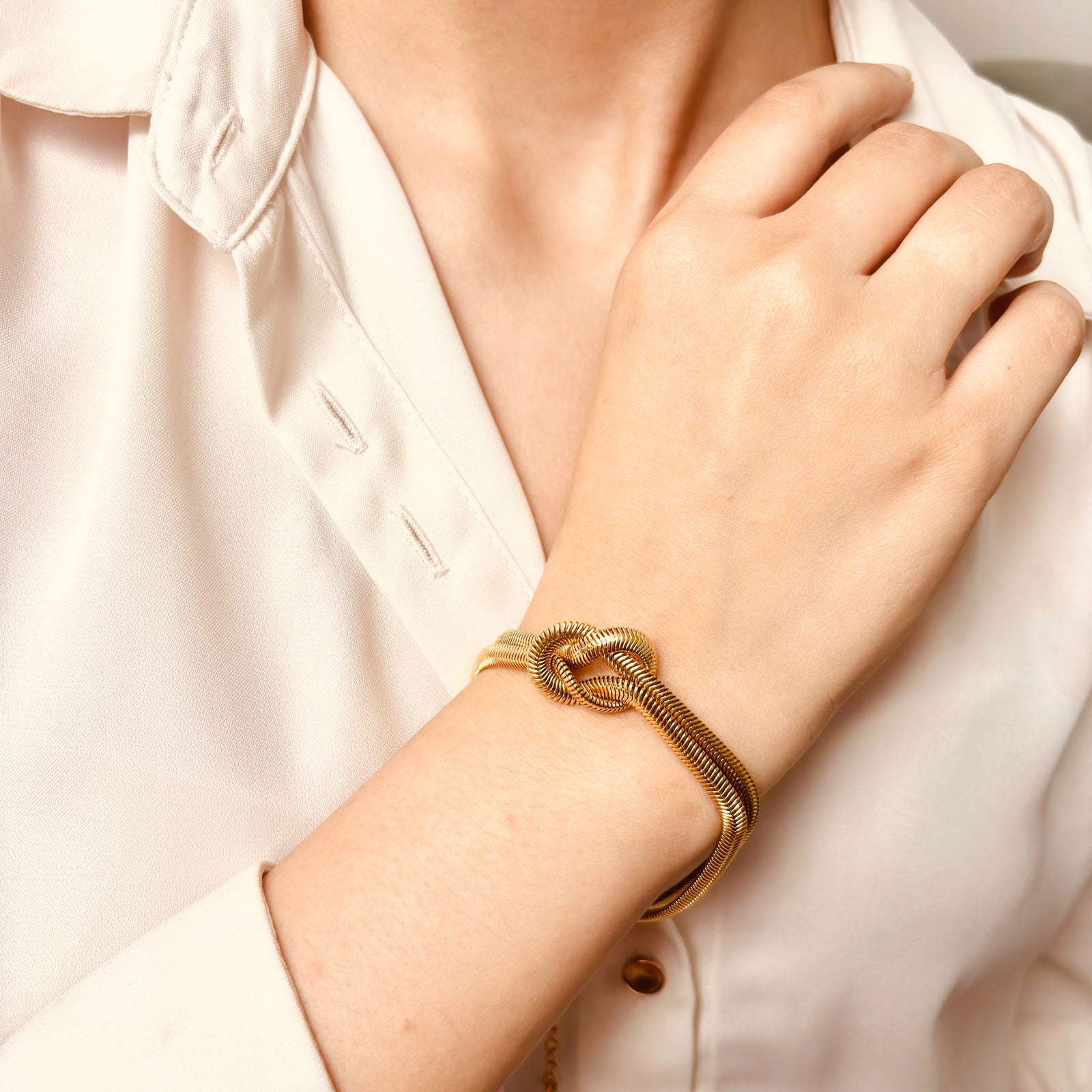 Model's hand close-up of snake chain texture and knotted center accent - dainty chic minimalist elegant gold plated bracelet - hypoallergenic anti‑tarnish waterproof nickel‑free lead‑free gold plated bracelet